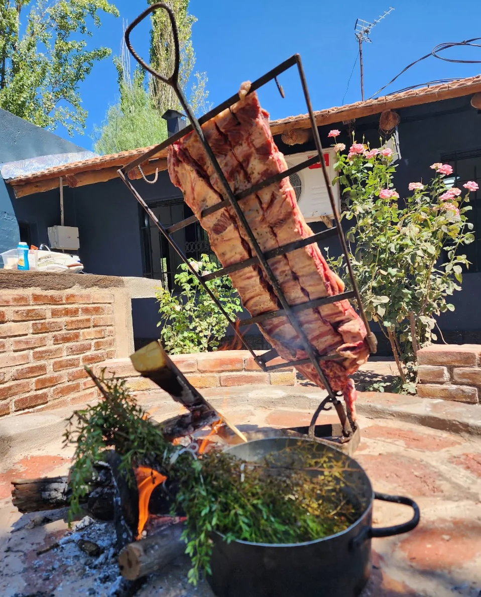 Asador vertical con carne cocinándose junto al fuego